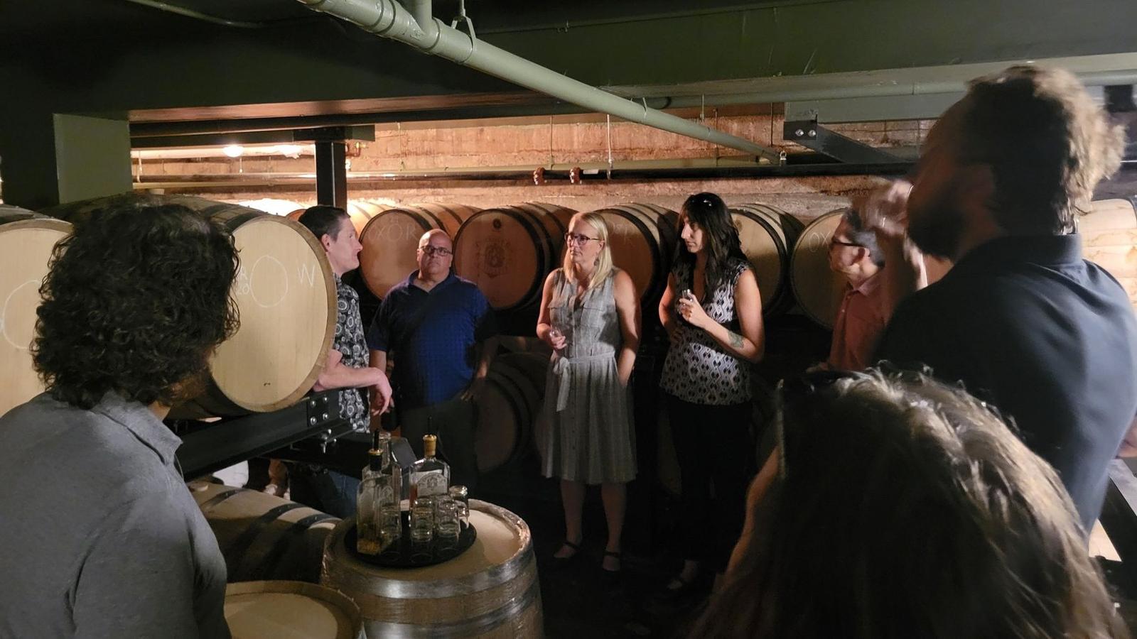 A guide leads a tasting for a tour group among the barrels in the barrel room