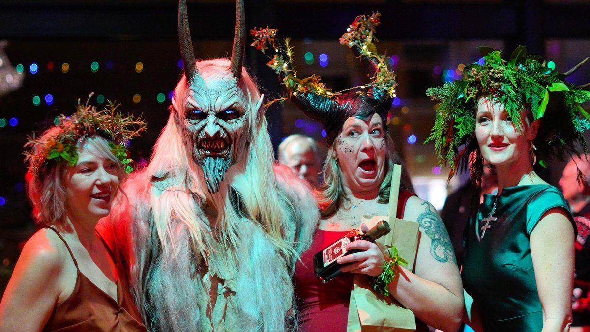 Krampus posing with costumed guests in evergreen crowns at Krampus Night