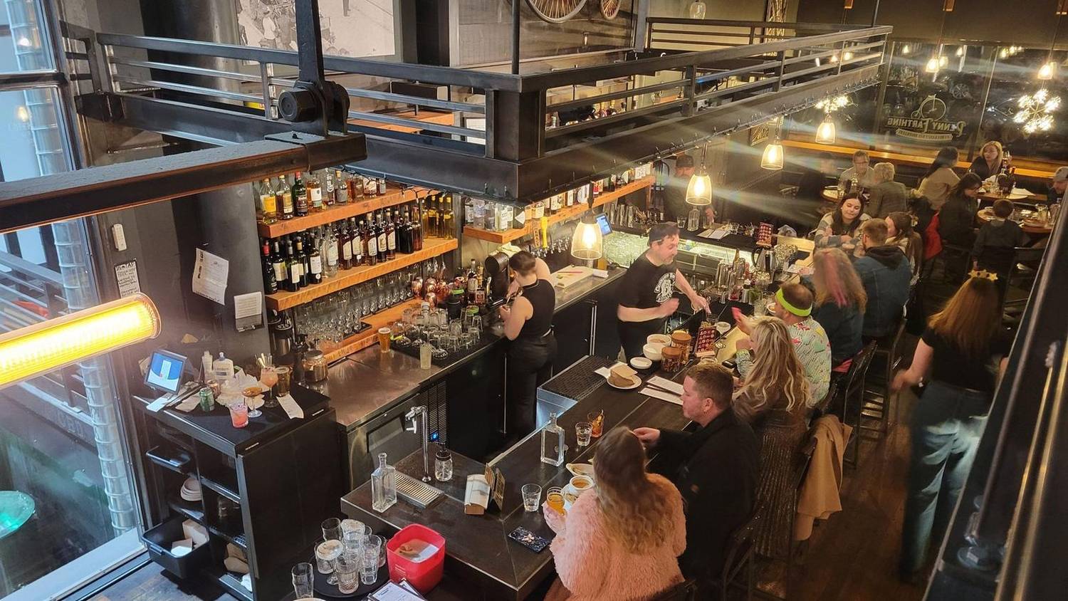 Looking down from the mezzanine at the Penny Farthing bar, with bartenders at work and guests along the bar