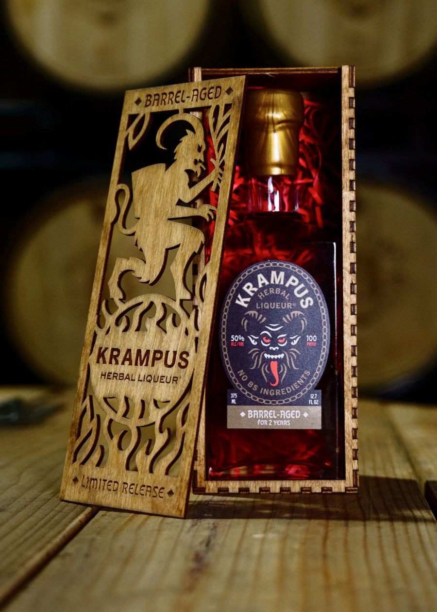 Bottle of barrel-aged Krampus Herbal Liqueur in a wooden box with decorative design