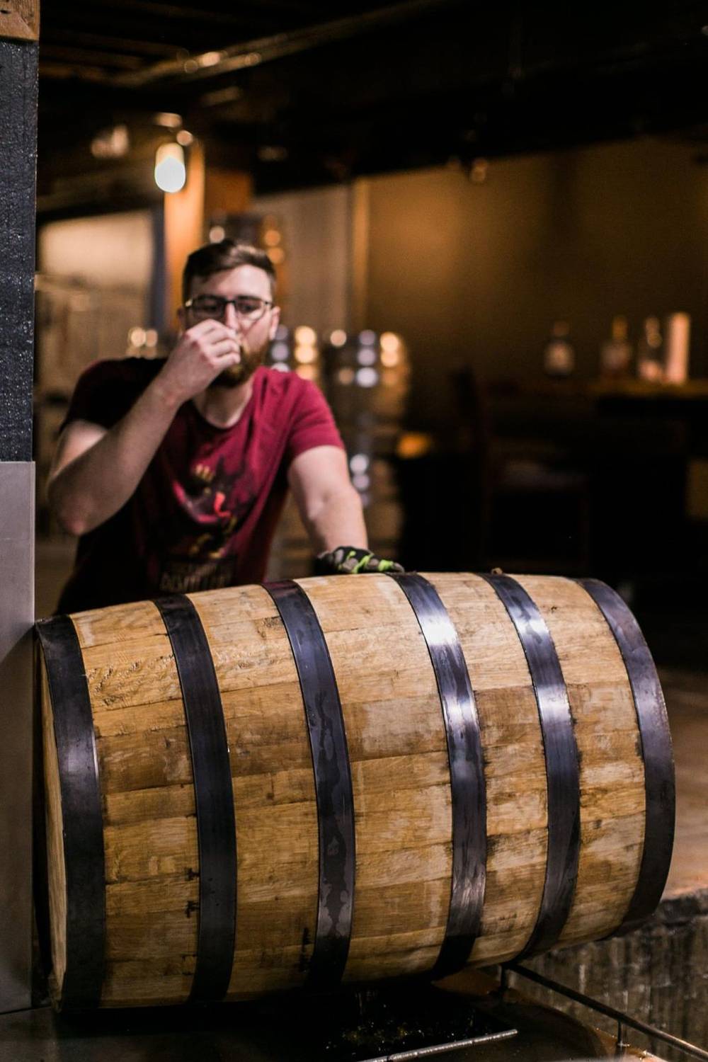 A distiller nosing whiskey straight from a bourbon barrel