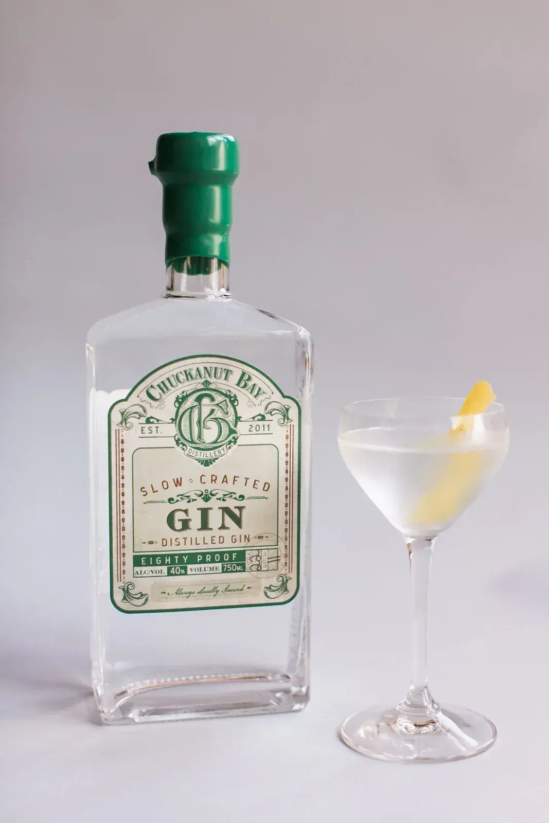 Chuckanut Gin beside a martini with a lemon twist