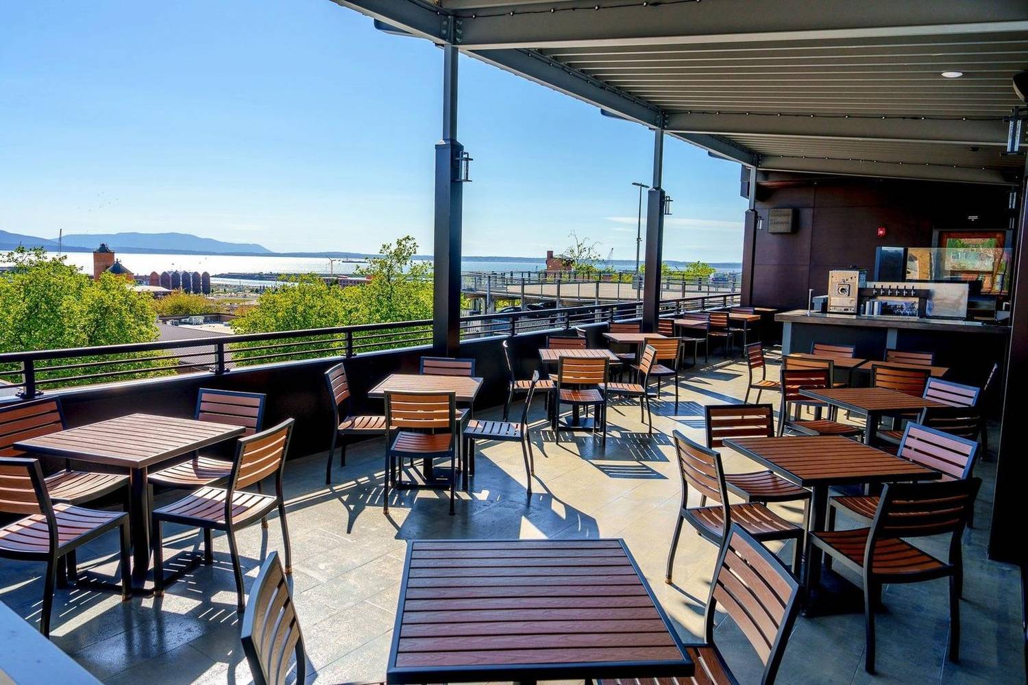 The rooftop bar on a sunny day, with tables under the covered deck and views over Bellingham Bay to the islands