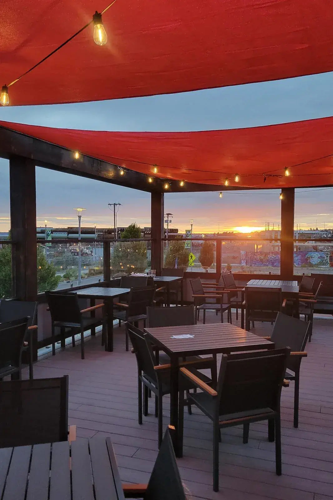 Bayside’s rooftop deck under red sails at sunset
